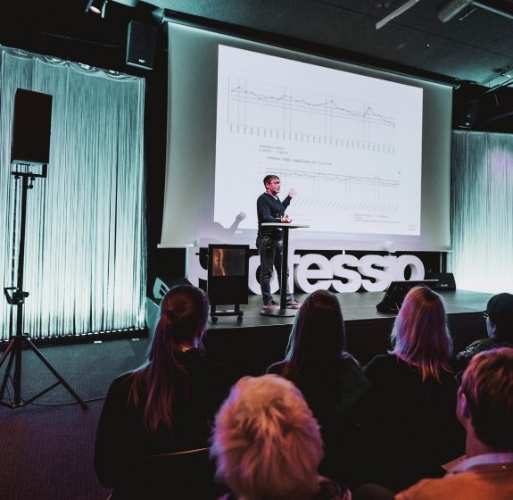 Kouluttaja, joka seisoo luokan edessä ja kouluttaa kuutta kouluttautujaa ja auttaa osaamisen kehittämisessä